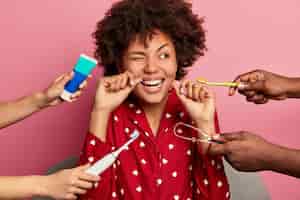 Foto grátis higiene oral e conceito de cuidados com os dentes. mulher de cabelo encaracolado limpa os dentes com fio dental, limpa a língua com limpador, usa escova e pasta de dente, posa em casa