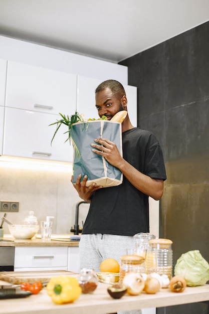 Hipster africano confiante blogueiro gravando vlog sobre culinária em uma câmera digital sentado em uma cozinha