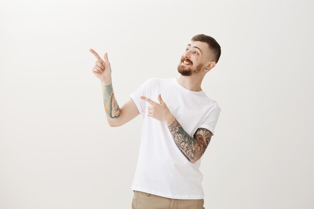 Hipster feliz e animado apontando e olhando para o canto superior esquerdo surpreso