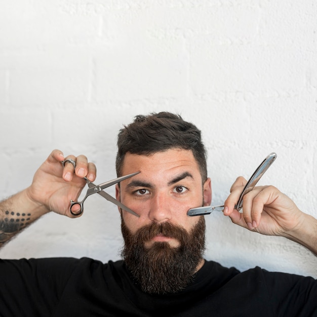 Hipster masculino mostrando ferramentas de cabeleireiros
