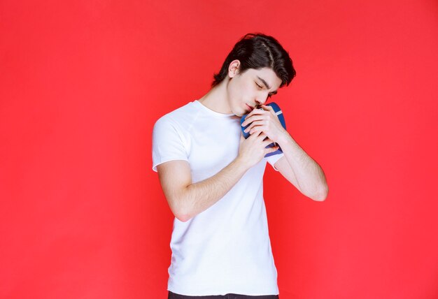 Homem abraçando e beijando sua caixa de presente azul.