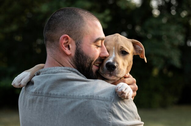 Foto grátis homem abraçando seu pitbull amigável