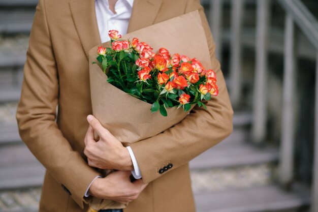 Homem abraçando um buquê de flores, dobrado em papel ofício.