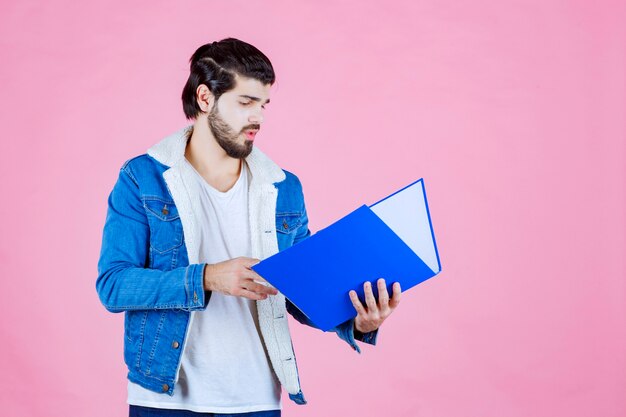 Homem abrindo uma pasta azul e verificando