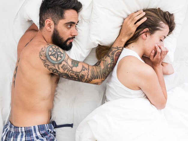Homem acariciando o cabelo da namorada enquanto estava deitado na cama