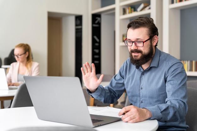 Homem acenando para laptop, tiro médio