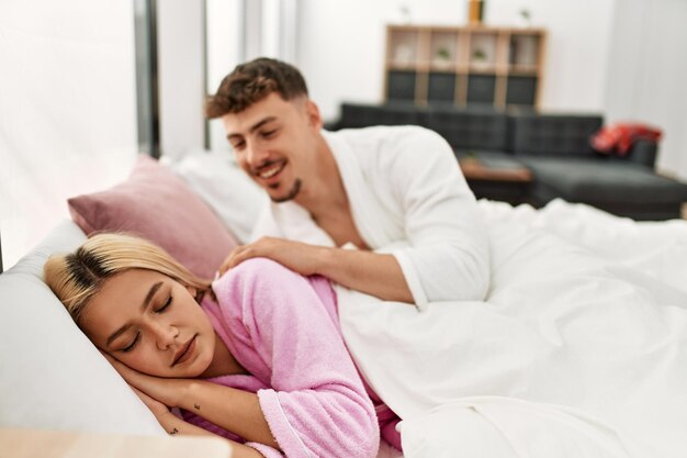 Homem acordando a namorada deitada na cama em casa.