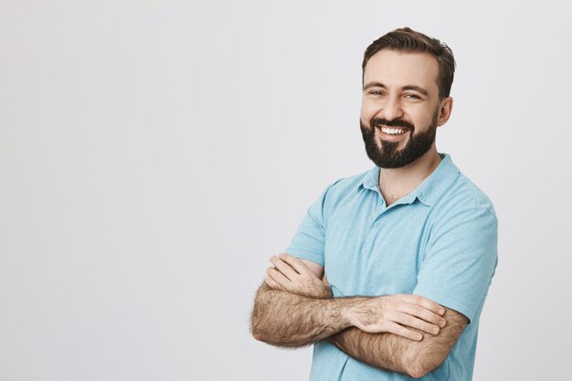 Homem adulto atraente a cruzar os braços e a sorrir.