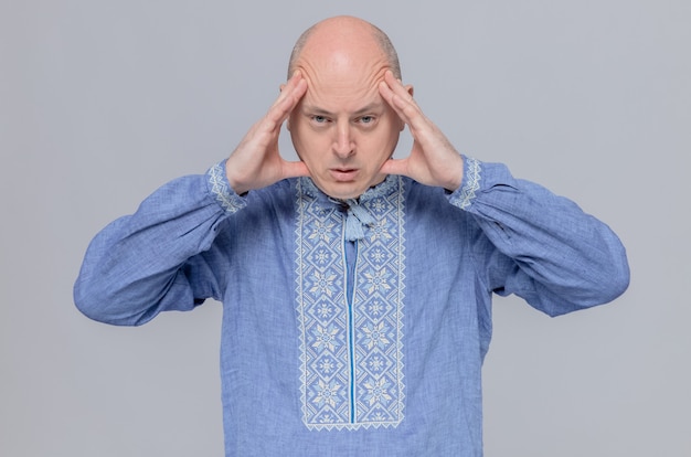 Foto grátis homem adulto confiante de camisa azul, segurando a cabeça e olhando