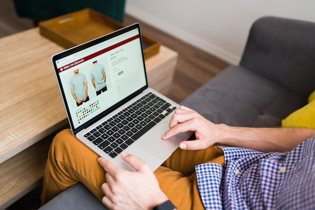 Homem adulto fazendo compras online durante um dia de lazer em casa. Jovem comprando roupas online