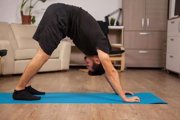 Homem adulto fazendo pose de ioga Dolphin em sua rotina de exercícios. Exercício saudável.