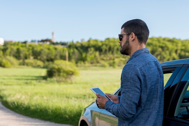 Homem adulto, ficar, perto, car, e, usando, tablete