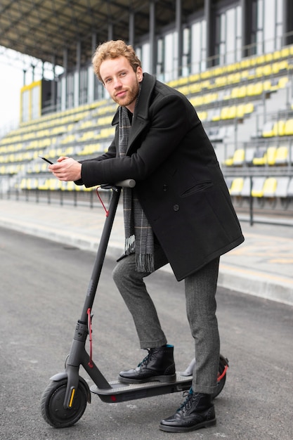 Homem adulto posando com sua scooter elétrica