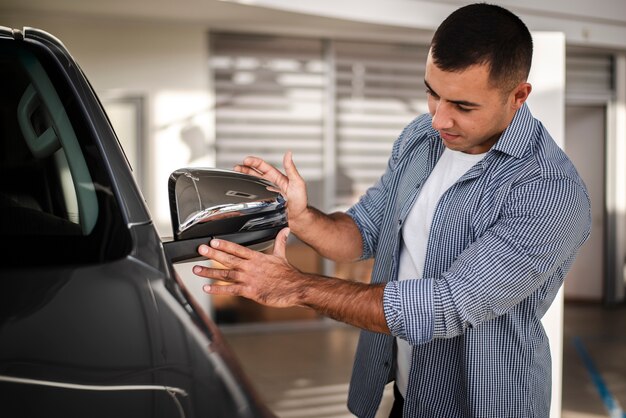 Foto grátis homem adulto, verificando um carro na concessionária