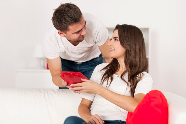 Homem afetuoso dando um pequeno presente vermelho para a namorada