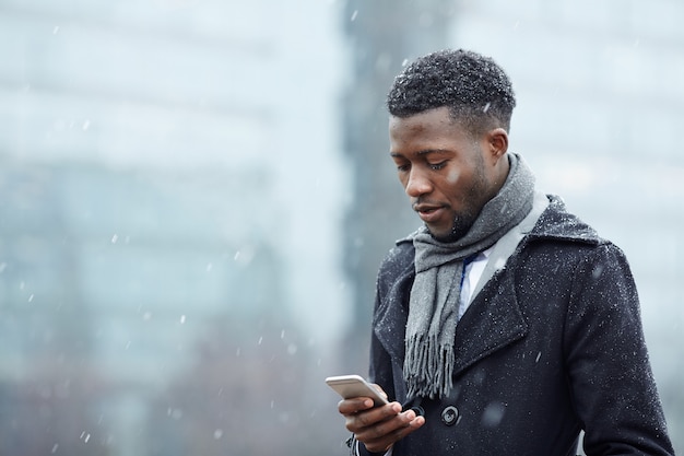 Homem Africano bonito com Smartphone na neve
