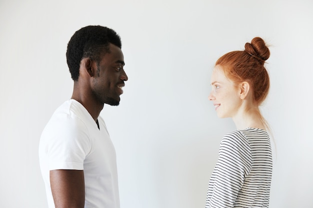 Homem africano com camiseta branca e mulher caucasiana ruiva com top listrado