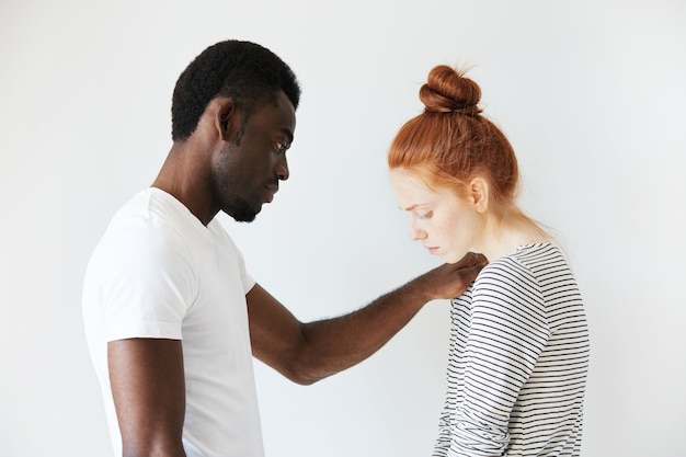 Homem africano com camiseta branca e mulher caucasiana ruiva com top listrado