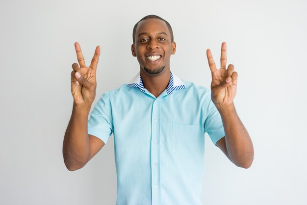 Homem africano considerável entusiasmado alegre que mostra sinais de paz e que olha a câmera.