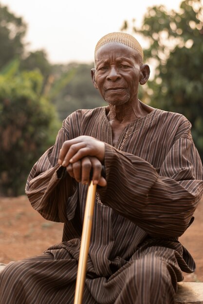 Homem africano de tiro médio sentado com bengala