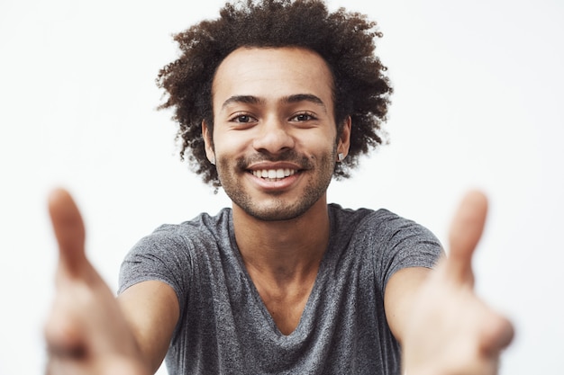 Homem africano feliz sorrindo esticando as mãos para a câmera.