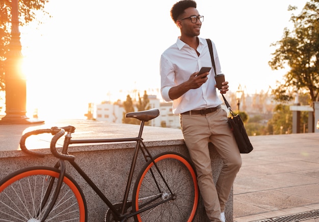 Homem africano no início da manhã em pé perto de bicicleta