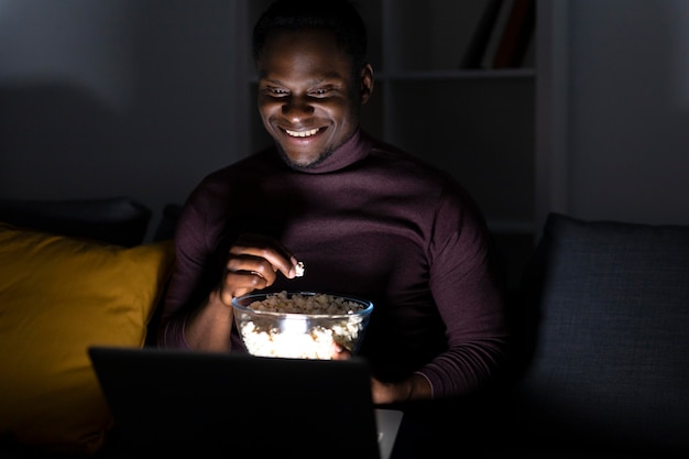 Foto grátis homem afro-americano assistindo serviço de streaming em casa sozinho