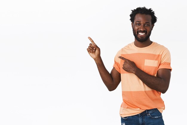 Homem afro-americano bonito apontando para o espaço da cópia