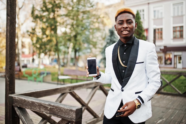 Homem afro-americano bonito chique de terno branco com telefone celular à mão