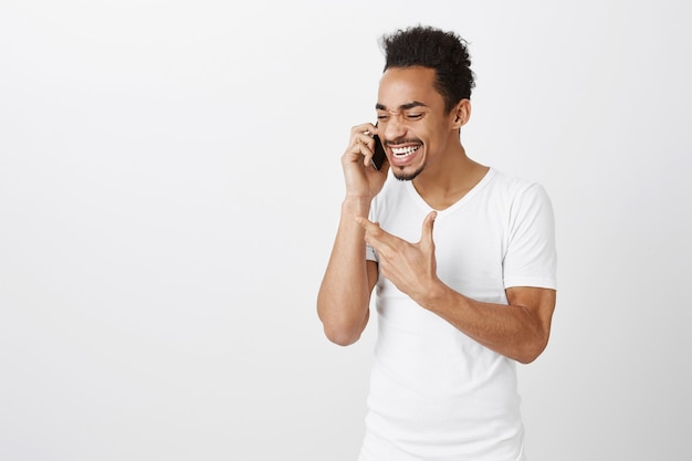Homem afro-americano bonito falando animadamente no celular, gesticulando enquanto explica algo