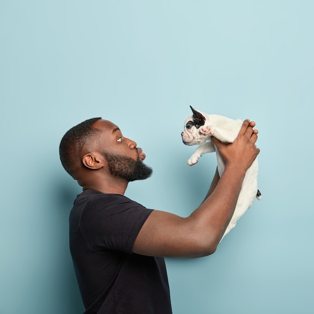 Homem afro-americano com camiseta preta segurando cachorro