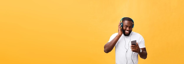 Homem afro-americano com fones de ouvido ouve e dança com música isolada em fundo amarelo