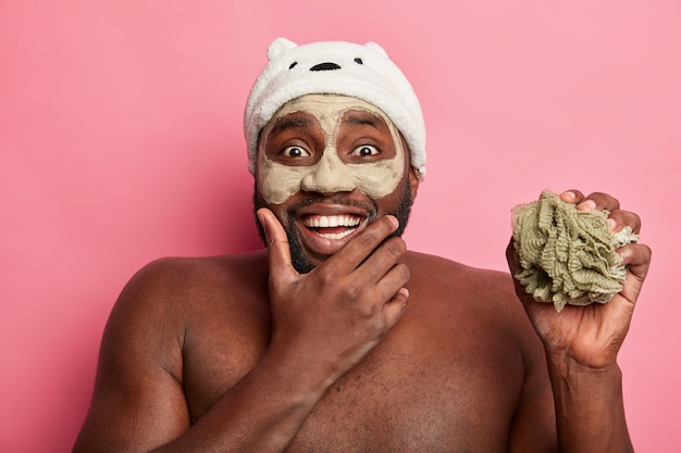 Homem afro-americano com máscara de argila, expressa emoções positivas isoladas