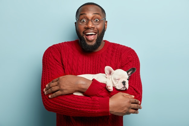 Homem afro-americano com suéter vermelho segurando cachorro