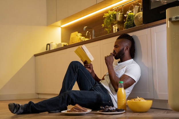 Foto grátis homem afro-americano comendo e lendo