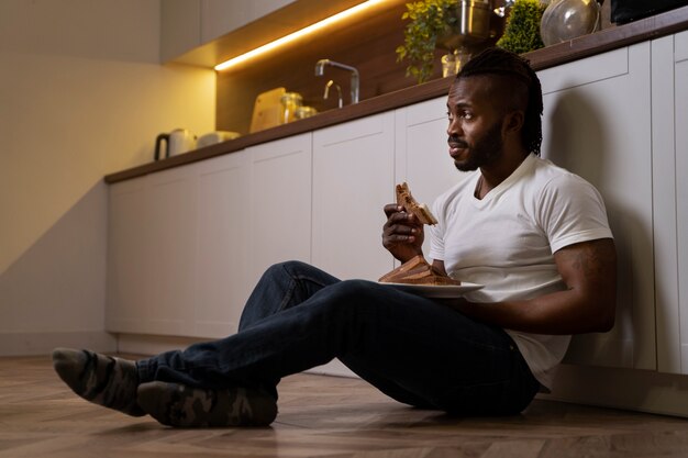 Homem afro-americano comendo no chão