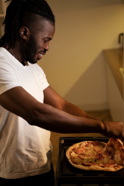 Homem afro-americano comendo pizza tarde da noite