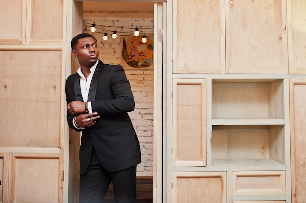 Foto grátis homem afro-americano forte e poderoso em terno preto posando contra estante de madeira