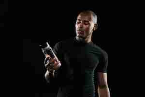Foto grátis homem afro-americano jovem esportes segurando a garrafa de água