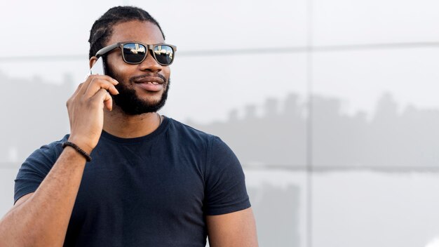 Homem afro-americano moderno falando ao telefone com espaço de cópia