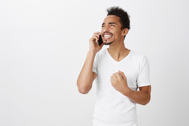 Homem afro-americano vencedor de sucesso triunfando sobre ótimas notícias enquanto fala ao telefone