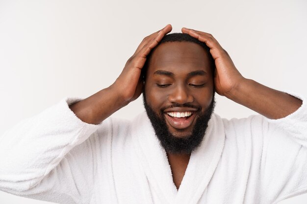 Homem afro-americano vestindo um roupão de banho com surpresa e emoção feliz isolado sobre fundo branco