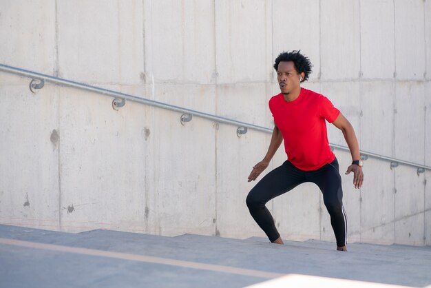 Homem afro-atlético fazendo exercício ao ar livre nas escadas. Esporte e estilo de vida saudável.