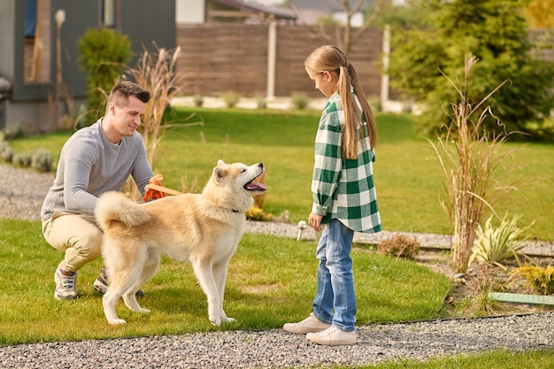 Homem agachado perto de cachorro e garota olhando ao ar livre