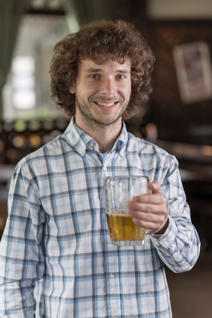 Homem alegre com cerveja no bar