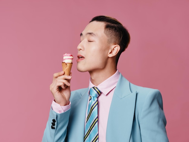 Homem alegre de terno azul gozo de sorvete fundo rosa Foto Premium