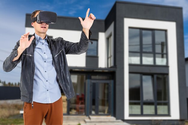 Homem alegre em óculos virtuais na frente da casa nova.