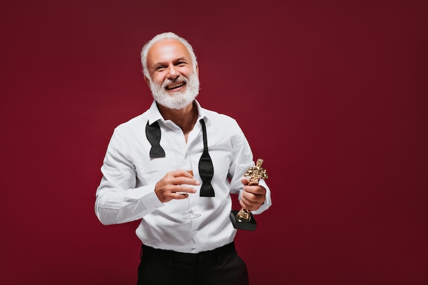 Homem alegre em roupas elegantes comemora a premiação com champanhe