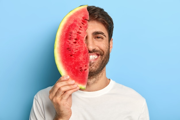 Homem alegre em um dia de verão segurando uma fatia de melancia