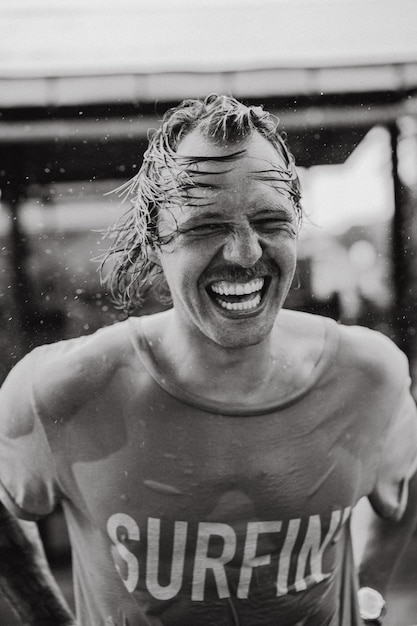 Foto grátis homem alegre em uma camiseta brilhante com um skate em um skatepark ri, salpicos de água de seu cabelo.